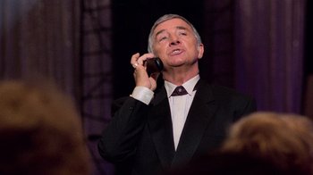 Movie still from “The Running Man” (1987), directed by Paul Michael Glaser – An older man talking on a cell phone while wearing a suit and tie; Close Up shot, Low angle