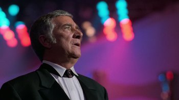 Movie still from “The Running Man” (1987), directed by Paul Michael Glaser – An older man wearing a suit and a tie; Close Up shot, Low angle