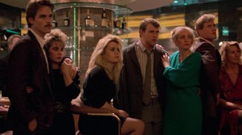 Movie still from “The Running Man” (1987), directed by Paul Michael Glaser – A group of people standing next to each other in a room; Medium shot, Low angle