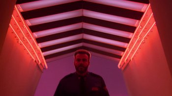 Movie still from “The Running Man” (1987), directed by Paul Michael Glaser – A man standing in a room with neon lights; Medium shot, Low angle