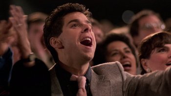Movie still from “The Running Man” (1987), directed by Paul Michael Glaser – A man in a suit and tie is laughing; Close Up shot, Low angle