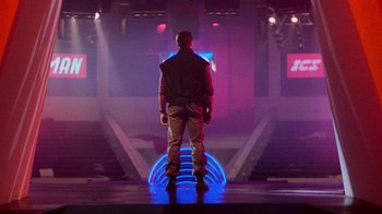 Movie still from “The Running Man” (1987), directed by Paul Michael Glaser – A man standing on a stage in front of lights; Wide shot, Low angle