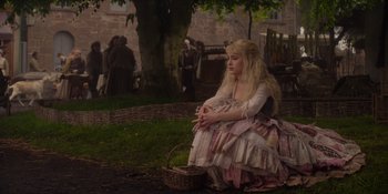 Movie still from “The School for Good and Evil” (2022), directed by Paul Feig – A woman sitting on the ground with a basket in front of her; Wide shot, High angle