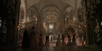 Movie still from “The School for Good and Evil” (2022), directed by Paul Feig – A group of people dressed in period costumes in an ornate hall; Extreme Wide shot, Low angle