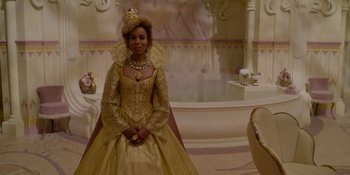 Movie still from “The School for Good and Evil” (2022), directed by Paul Feig – A woman in a gold dress and a crown; Medium shot, Over the shoulder angle
