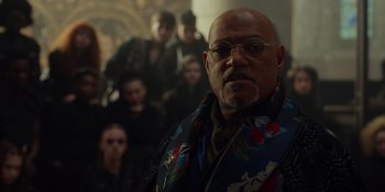 Movie still from “The School for Good and Evil” (2022), directed by Paul Feig – An older bald man wearing glasses and a floral shirt; Close Up shot, Over the shoulder angle