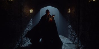 Movie still from “The School for Good and Evil” (2022), directed by Paul Feig – A man in a black cape holding a candle; Wide shot, Low angle