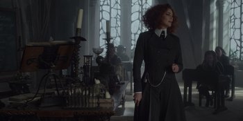 Movie still from “The School for Good and Evil” (2022), directed by Paul Feig – A woman standing in front of a table in a room; Medium shot, Over the shoulder angle