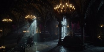 Movie still from “The School for Good and Evil” (2022), directed by Paul Feig – A woman sitting on a chair in a room with chandeliers; Extreme Wide shot, High angle