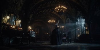 Movie still from “The School for Good and Evil” (2022), directed by Paul Feig – A woman in a black dress in a dark room with chandeliers; Wide shot, Low angle