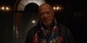Movie still from “The School for Good and Evil” (2022), directed by Paul Feig – A bald man with glasses wearing a floral scarf; Close Up shot, Low angle