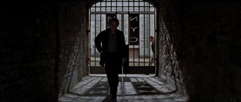 Movie still from “The Score” (2001), directed by Frank Oz – A man walking down a stone walkway in front of a building; Wide shot, Low angle