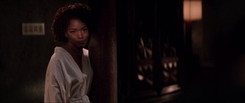 Movie still from “The Score” (2001), directed by Frank Oz – A woman standing next to a wooden pillar; Medium shot, Over the shoulder angle