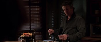 Movie still from “The Score” (2001), directed by Frank Oz – A man holding a spoon in his hand while sitting at a dinner table; Medium shot, Over the shoulder angle