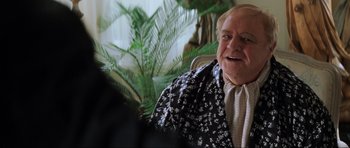 Movie still from “The Score” (2001), directed by Frank Oz – An older man sitting in front of a green plant; Close Up shot, Over the shoulder angle