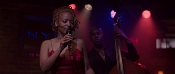 Movie still from “The Score” (2001), directed by Frank Oz – A woman singing into a microphone in front of a man; Medium shot, Over the shoulder angle