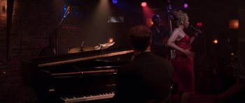 Movie still from “The Score” (2001), directed by Frank Oz – A man sitting at a piano in front of a group of people; Medium shot, Over the shoulder angle