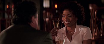 Movie still from “The Score” (2001), directed by Frank Oz – A woman sitting at a table holding a wine glass; Close Up shot, Over the shoulder angle