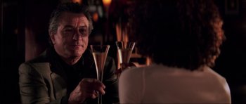 Movie still from “The Score” (2001), directed by Frank Oz – A man sitting at a table holding a wine glass; Close Up shot, Over the shoulder angle