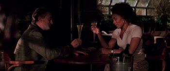 Movie still from “The Score” (2001), directed by Frank Oz – A man and a woman sitting at a table holding wine glasses; Medium shot, Over the shoulder angle