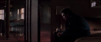 Movie still from “The Score” (2001), directed by Frank Oz – A man sitting in a dark room next to a window; Medium shot, Low angle