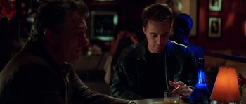 Movie still from “The Score” (2001), directed by Frank Oz – Two men sitting at a table in front of drinks; Medium shot, Over the shoulder angle