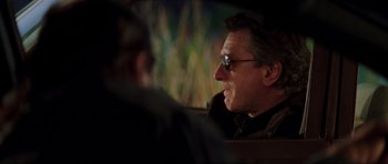 Movie still from “The Score” (2001), directed by Frank Oz – A person in a car wearing sunglasses; Close Up shot, Over the shoulder angle