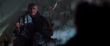 Movie still from “The Score” (2001), directed by Frank Oz – An older man sitting on a chair in a room; Medium shot, Over the shoulder angle