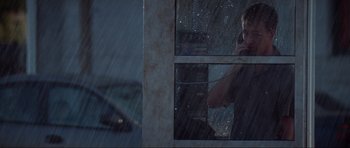 Movie still from “The Score” (2001), directed by Frank Oz – A man on a cell phone looking out of a window in the rain; Medium shot, Low angle