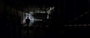 Movie still from “The Score” (2001), directed by Frank Oz – A man standing in a dark room next to a metal fence; Extreme Wide shot, High angle