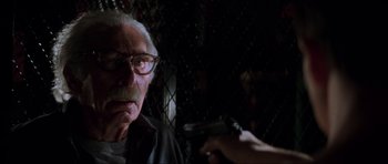 Movie still from “The Score” (2001), directed by Frank Oz – An older man with glasses is holding a gun; Close Up shot, Over the shoulder angle