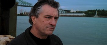 Movie still from “The Score” (2001), directed by Frank Oz – A person wearing a black shirt near a body of water; Close Up shot, Low angle