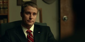 Movie still from “Dopesick” (2021), directed by Danny Strong – A person wearing a suit and tie; Close Up shot, Over the shoulder angle