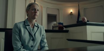 Movie still from “Dopesick” (2021), directed by Danny Strong – A woman sitting at a table in a room; Medium shot, Low angle