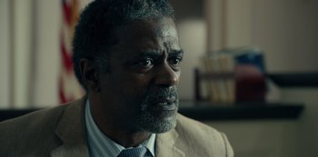 Movie still from “Dopesick” (2021), directed by Danny Strong – An older black man wearing a suit and tie; Close Up shot, Over the shoulder angle