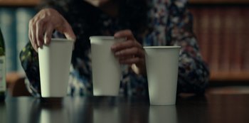 Movie still from “Dopesick” (2021), directed by Danny Strong – A person is holding a paper coffee cup in their hand; Extreme Close Up shot, High angle