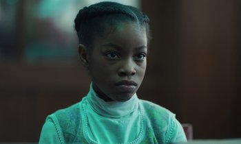 Movie still from “The Silent Twins” (2022), directed by Agnieszka Smoczynska – A young woman with blue hair is looking at the camera; Close Up shot, Over the shoulder angle