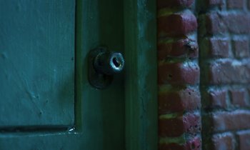 Movie still from “The Silent Twins” (2022), directed by Agnieszka Smoczynska – A door knob on a green door; Extreme Close Up shot, High angle