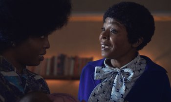 Movie still from “The Silent Twins” (2022), directed by Agnieszka Smoczynska – Two women talking to each other in front of a bookshelf; Close Up shot, Over the shoulder angle