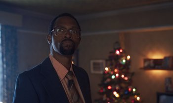 Movie still from “The Silent Twins” (2022), directed by Agnieszka Smoczynska – A man in a suit and tie standing in front of a christmas tree; Close Up shot, Low angle