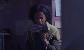 Movie still from “The Silent Twins” (2022), directed by Agnieszka Smoczynska – A woman looking at a piece of paper in her hands; Close Up shot, Over the shoulder angle