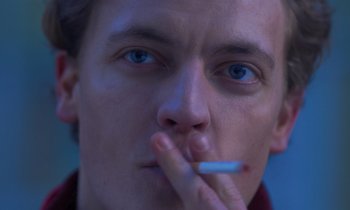 Movie still from “The Silent Twins” (2022), directed by Agnieszka Smoczynska – A person smoking a cigarette; Extreme Close Up shot, Low angle