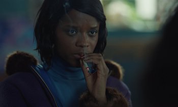 Movie still from “The Silent Twins” (2022), directed by Agnieszka Smoczynska – A woman is holding a cell phone up to her mouth; Close Up shot, Over the shoulder angle