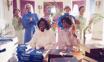 Movie still from “The Silent Twins” (2022), directed by Agnieszka Smoczynska – A group of women sitting in front of a table; Medium shot, Over the shoulder angle