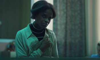 Movie still from “The Silent Twins” (2022), directed by Agnieszka Smoczynska – A woman in a white shirt is looking at the camera; Medium shot, Low angle