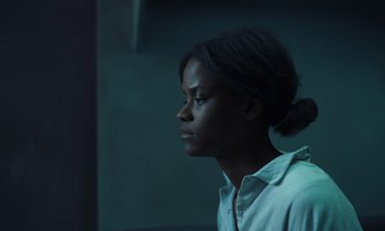 Movie still from “The Silent Twins” (2022), directed by Agnieszka Smoczynska – A young man with long black hair looking to his left; Close Up shot, High angle