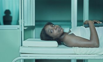 Movie still from “The Silent Twins” (2022), directed by Agnieszka Smoczynska – A woman laying on a bed looking up at the sky; Medium shot, Overhead angle