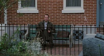 Movie still from “The Sixth Sense” (1999), directed by M. Night Shyamalan – A man sitting on top of a green park bench; Wide shot, Low angle