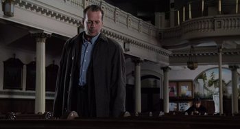 Movie still from “The Sixth Sense” (1999), directed by M. Night Shyamalan – A man standing in front of pews in a church; Medium shot, Low angle