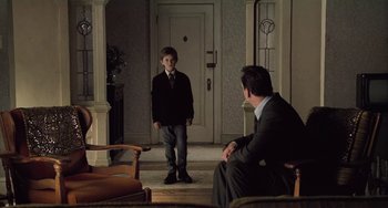 Movie still from “The Sixth Sense” (1999), directed by M. Night Shyamalan – A man and a boy in a suit and tie in front of a door; Wide shot, Over the shoulder angle